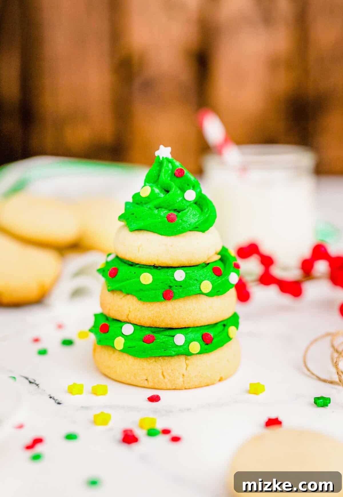 A large sugar cookie forms the base of the tree, a medium-sized cookie sits in the middle, and a small cookie crowns the top, all expertly sandwiched with smooth green icing and festive sprinkles.