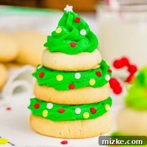 Three sugar cookies are stacked with green icing and sprinkles to resemble a Christmas tree, ready for a festive display.