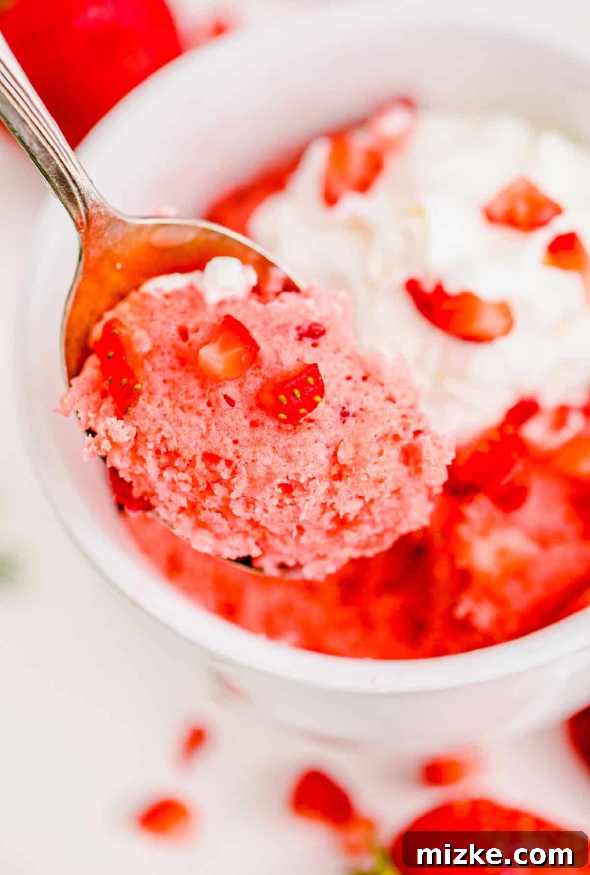 Spoonful of light and fluffy strawberry mug cake with fresh diced strawberries