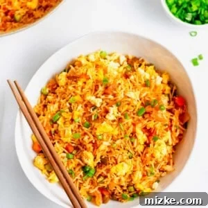 Overhead view of kimchi fried rice in white bowl with wooden chopsticks