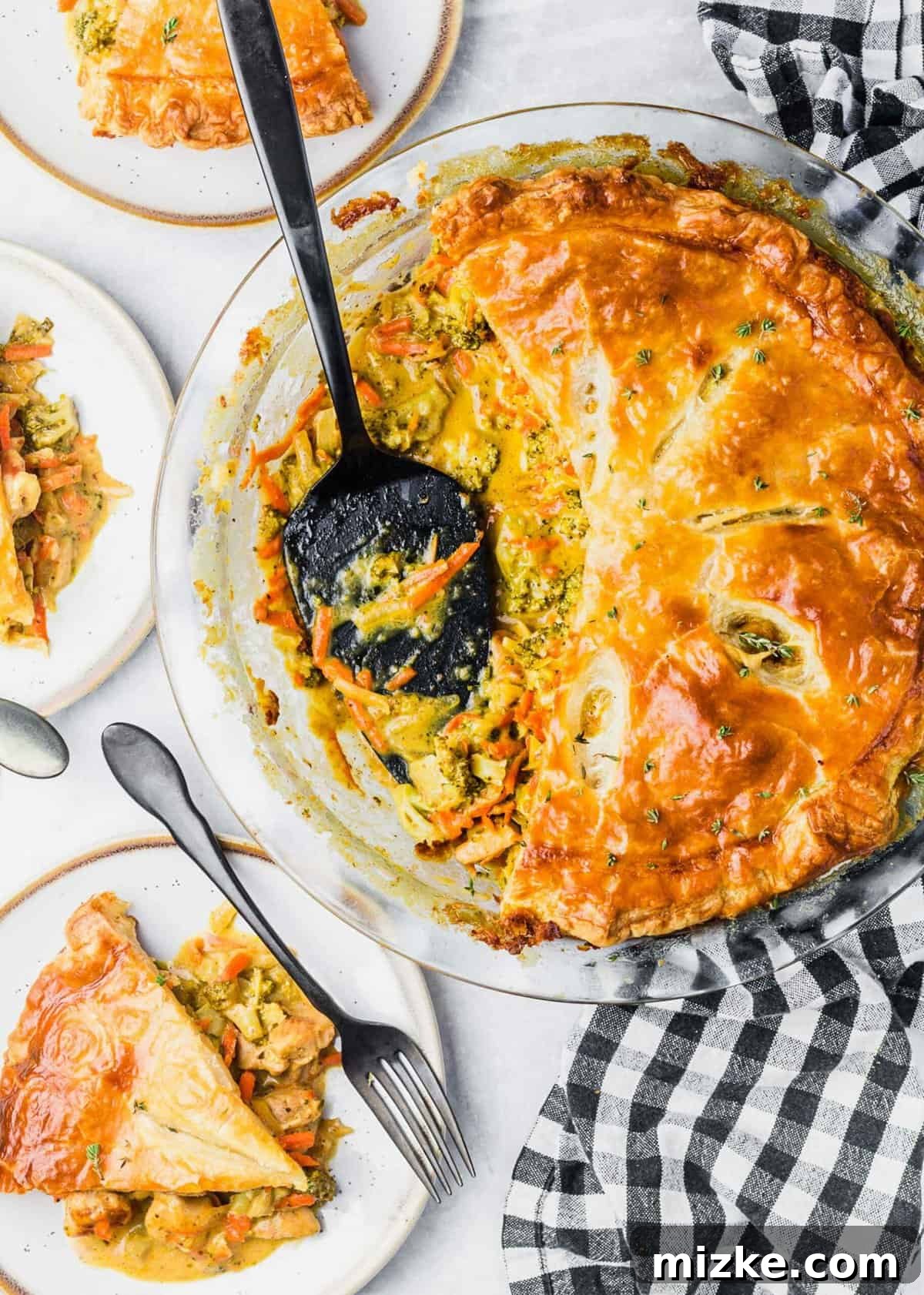 Golden-Baked Cheesy Chicken & Broccoli Pot Pie 5 Overhead view of a cooked pot pie in a baking dish with a spoon, showing a spoonful removed