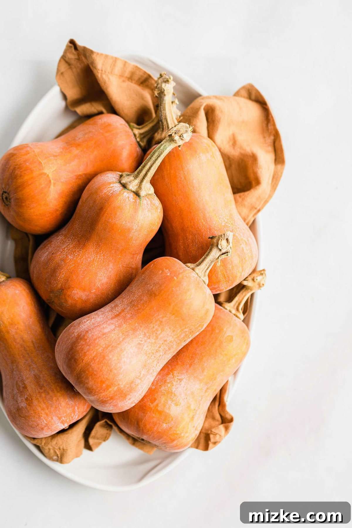 Caramelized Honeynut Squash 3 A bountiful pile of perfectly roasted honeynut squash halves, showcasing their golden-brown edges and tender texture, arranged on a serving platter.