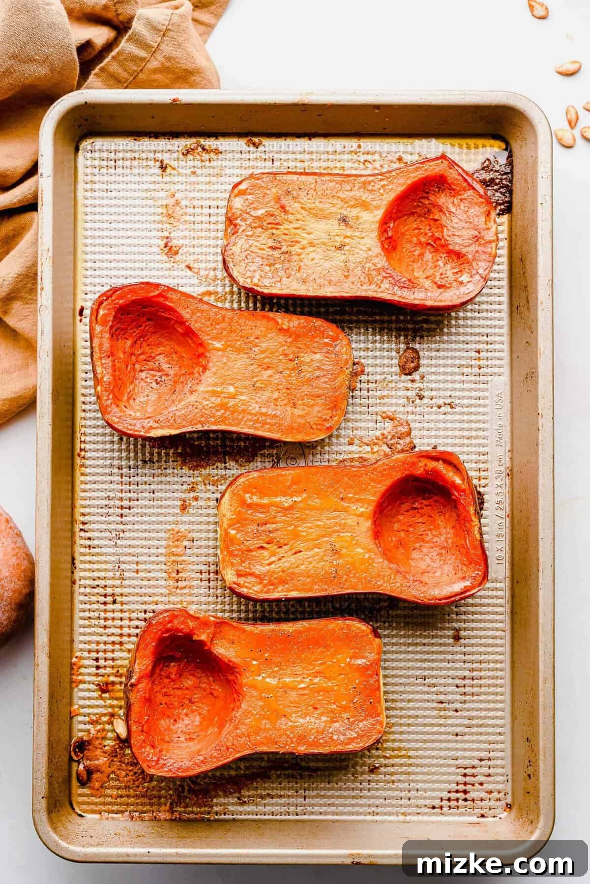 Caramelized Honeynut Squash 5 Honeynut squash halves arranged neatly cut-side down on a baking sheet, precisely positioned for even roasting in the oven.