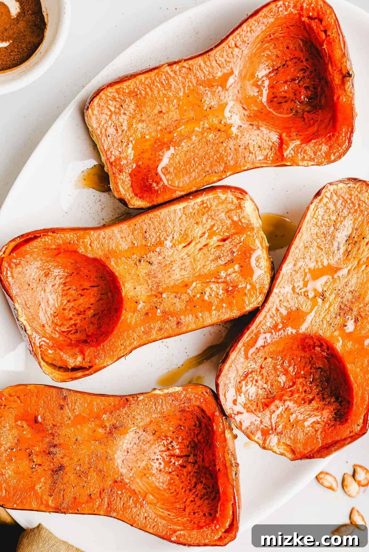 Caramelized Honeynut Squash 7 Beautifully roasted honeynut squash halves, glistening and golden, arranged artfully on a pristine white serving platter, ready to be devoured.