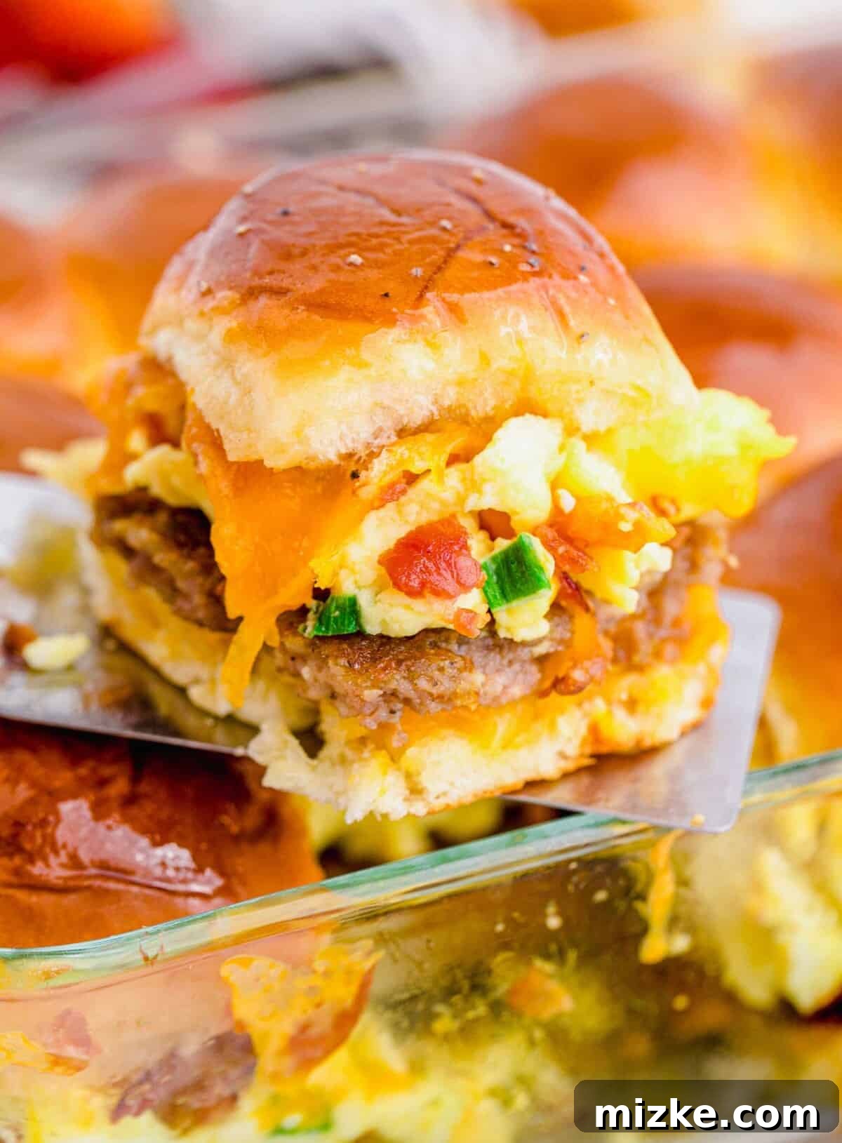 Morning Bites 2 Breakfast slider being lifted out of baking dish, highlighting melted cheese and fluffy bun