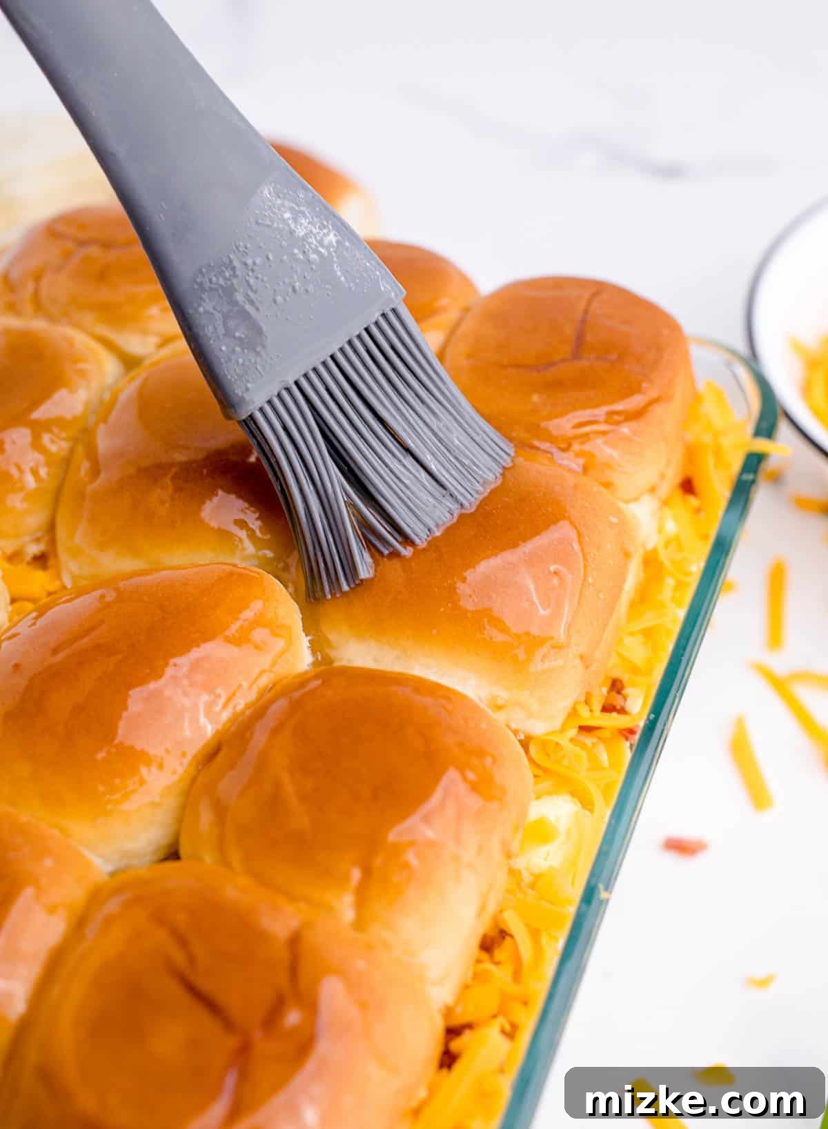 Morning Bites 16 A silicone brush applying melted maple butter generously over the top halves of the slider buns, creating a glossy finish