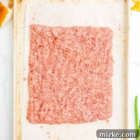Raw pork sausage pressed into a square on a metal baking sheet