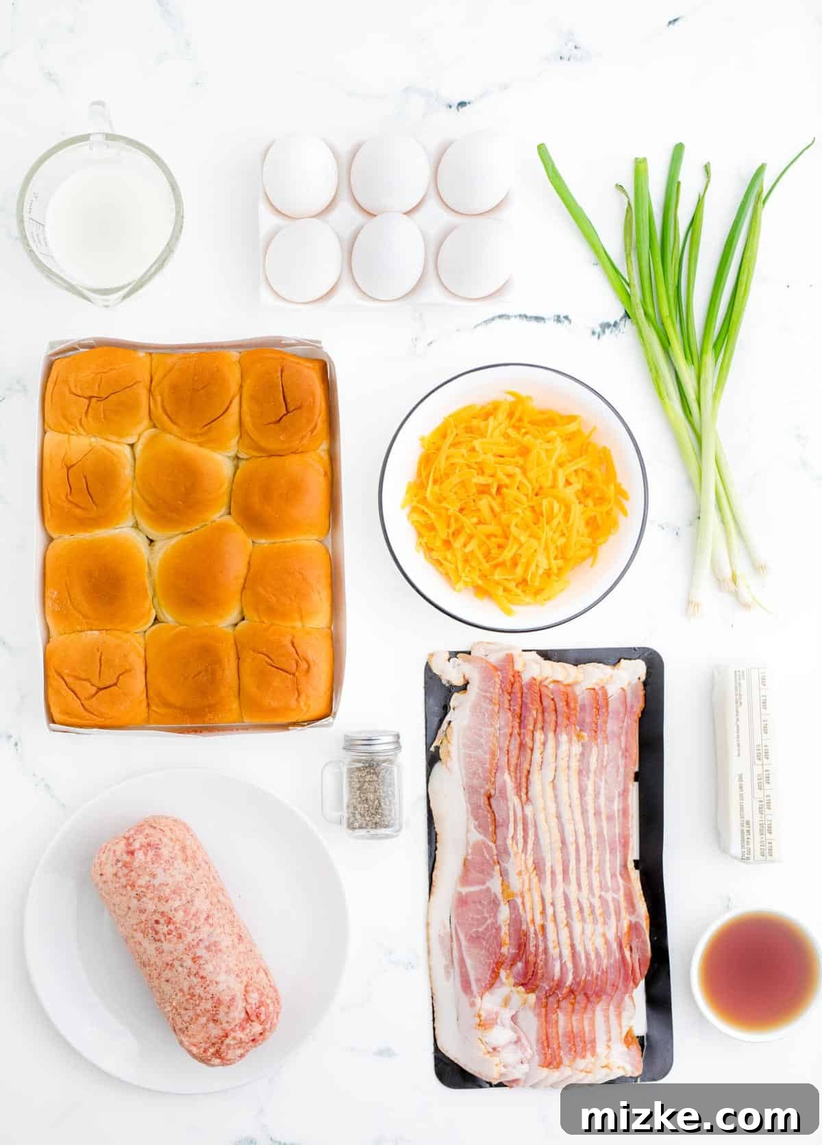 Morning Bites 3 A vibrant display of fresh ingredients laid out for making breakfast sliders, including rolls, sausage, bacon, eggs, cheese, and green onions