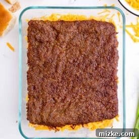 Baked pork sausage square placed on top of shredded cheddar cheese