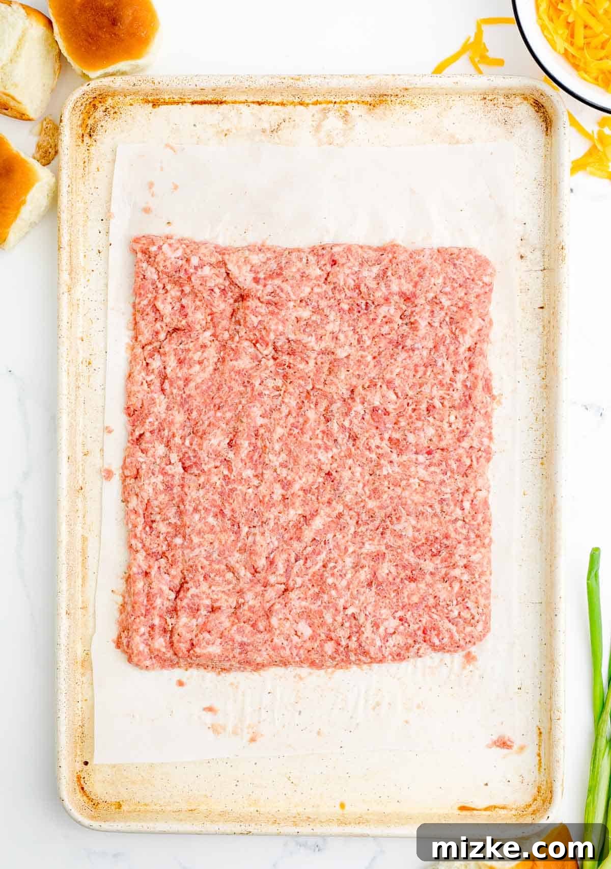 Morning Bites 5 Raw pork sausage pressed into a neat rectangle on a parchment-lined metal baking sheet, ready for baking