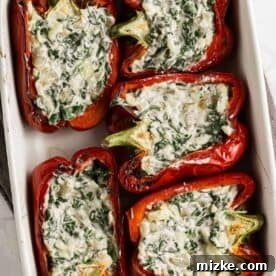 The creamy spinach ricotta mixture being carefully spooned into tender red bell pepper halves.