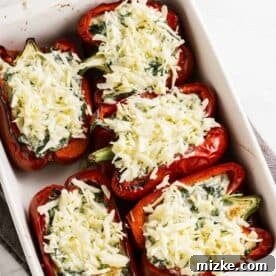 Shredded mozzarella cheese generously sprinkled over the tops of the stuffed bell pepper halves, ready for baking.