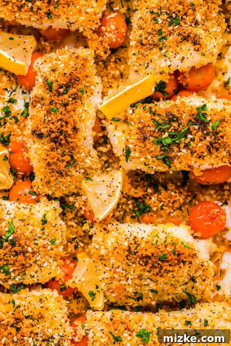 Crispy Everything Bagel Cod 3 Baked cod fillets topped with vibrant cherry tomatoes and fresh lemon slices, in a white baking dish.