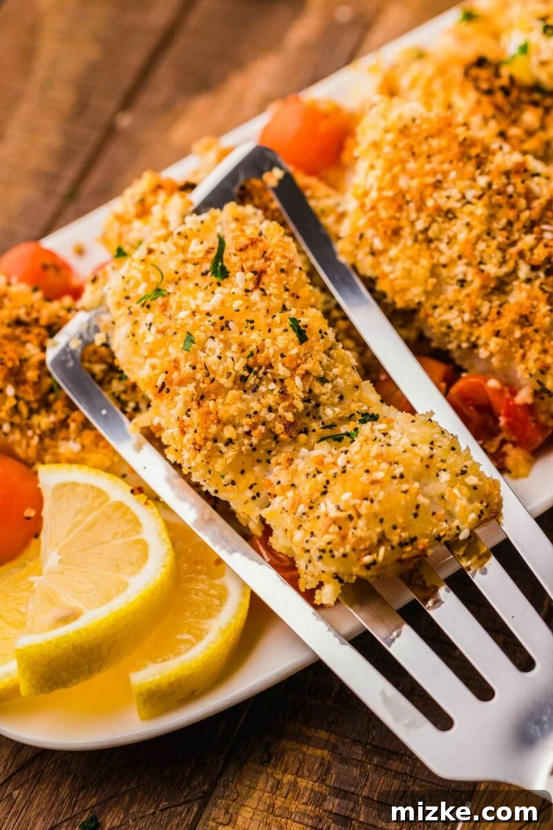 Crispy Everything Bagel Cod 5 A piece of baked everything bagel crusted cod is being lifted by a spatula from the serving dish, showcasing its crispy texture.