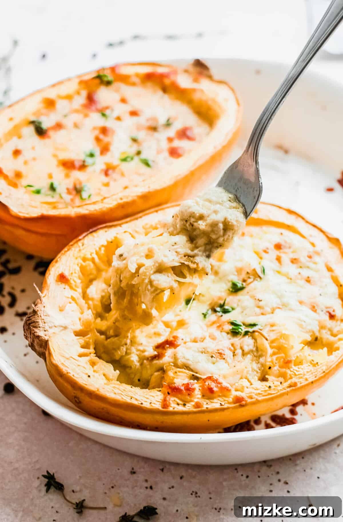 Fork lifting cheesy spaghetti squash out of squash half