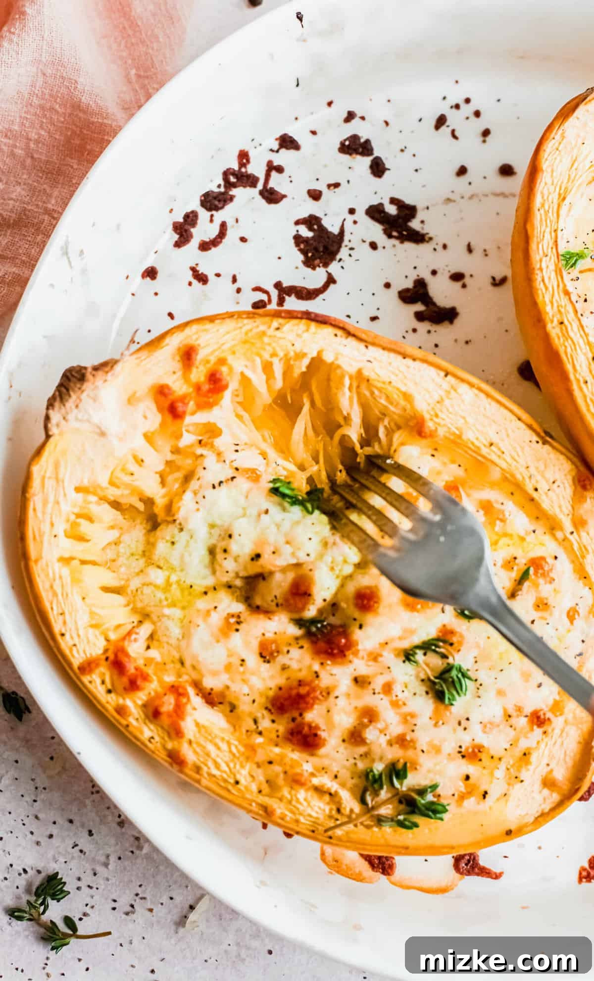 Overhead view of fork shredding baked cheesy spaghetti squash