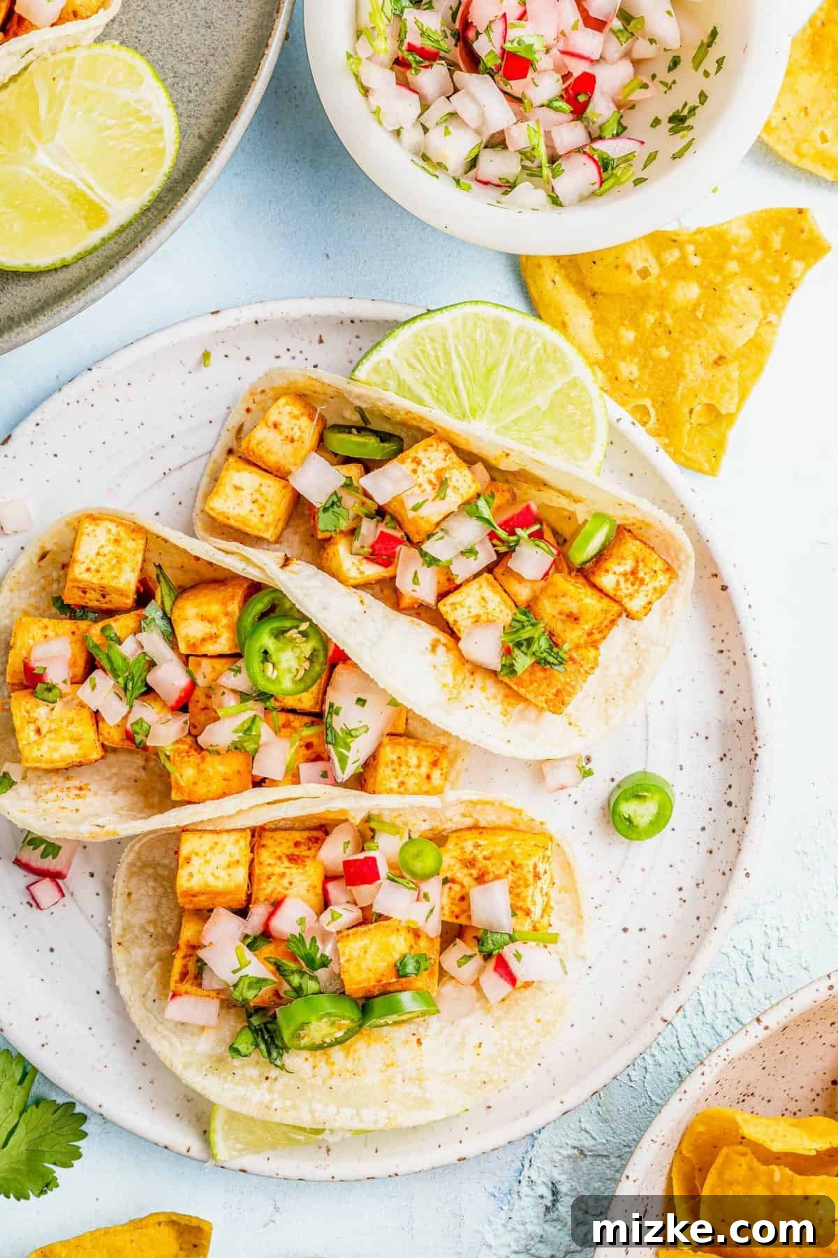 Streetwise Tofu Tacos 2 Three tofu tacos on plate with lime wedge and tortilla chips