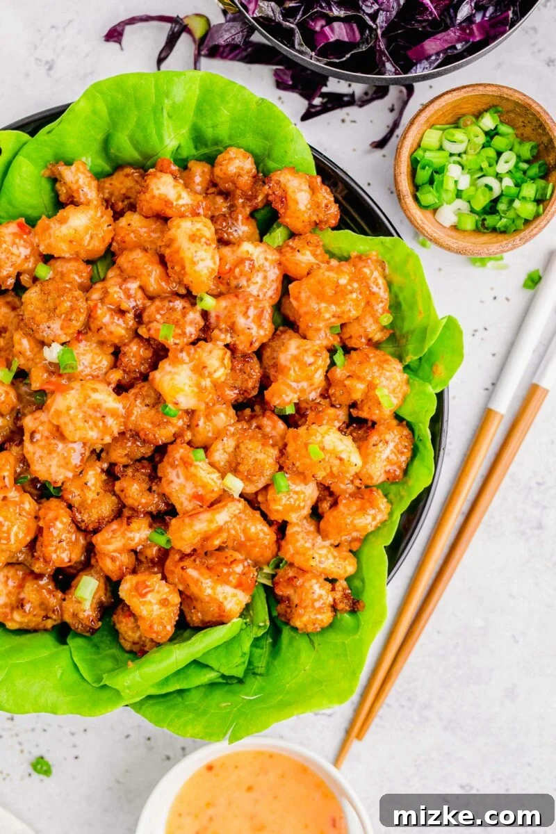 Dynamite Shrimp 2 A large serving of bang bang shrimp is presented on green lettuce in a large black serving bowl.