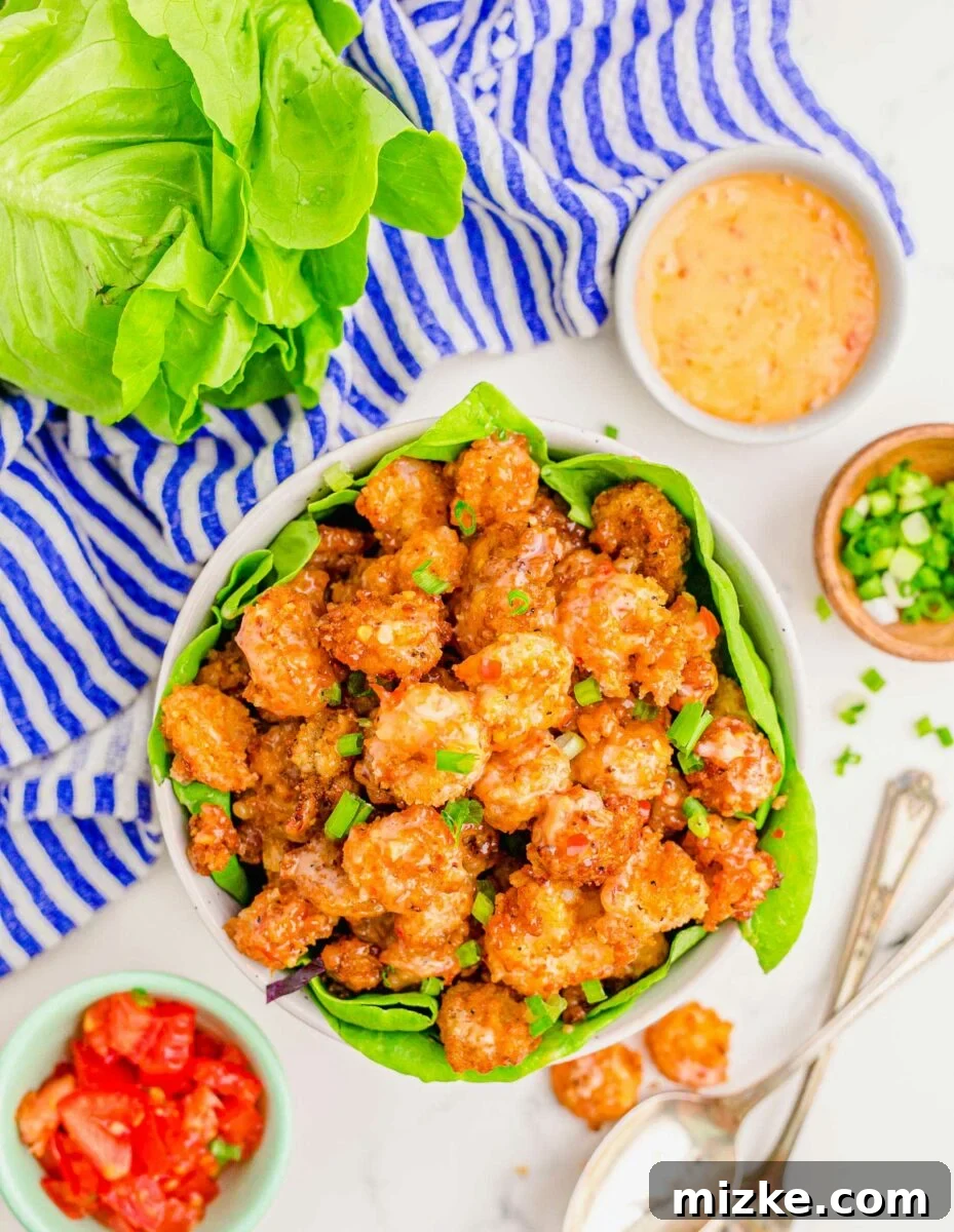 Dynamite Shrimp 15 A large white bowl lined with lettuce is filled with cooked bang bang shrimp.