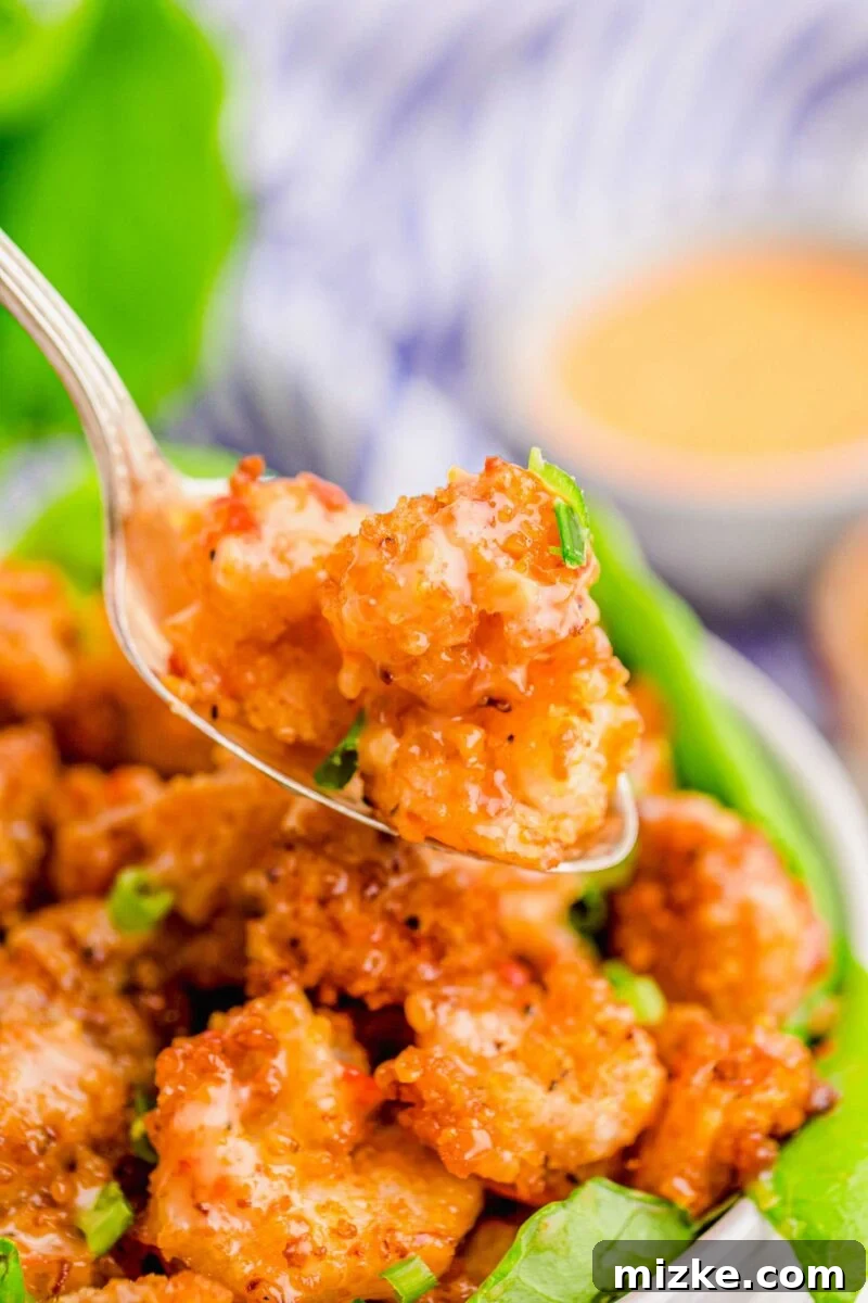 Dynamite Shrimp 16 A spoon is lifting a portion of bang bang shrimp from the bowl.