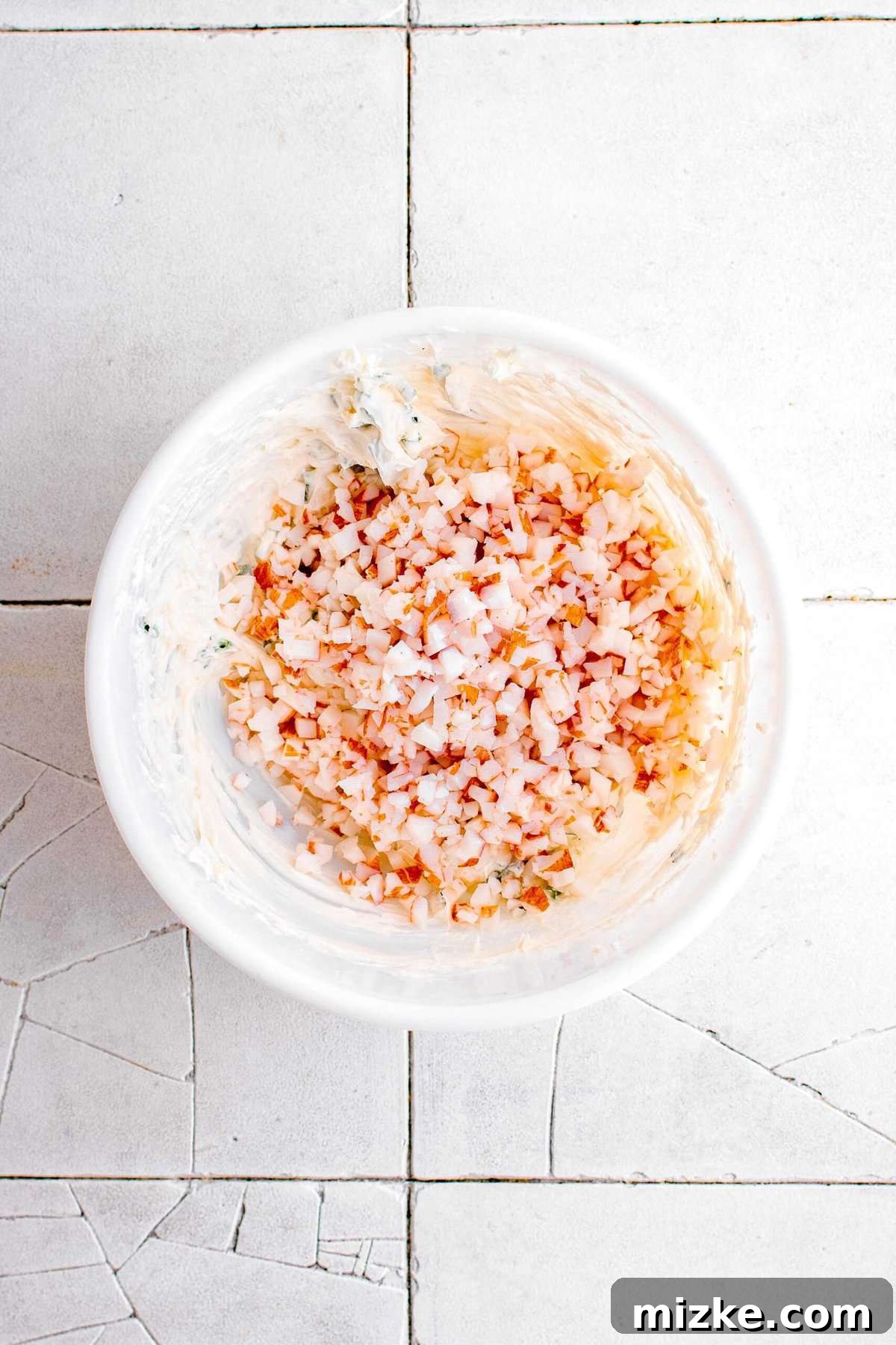 Golden Crispy Crab Bites 7 Finely shredded imitation crab meat being carefully added into the smooth cream cheese mixture in a white bowl, ready for combining.