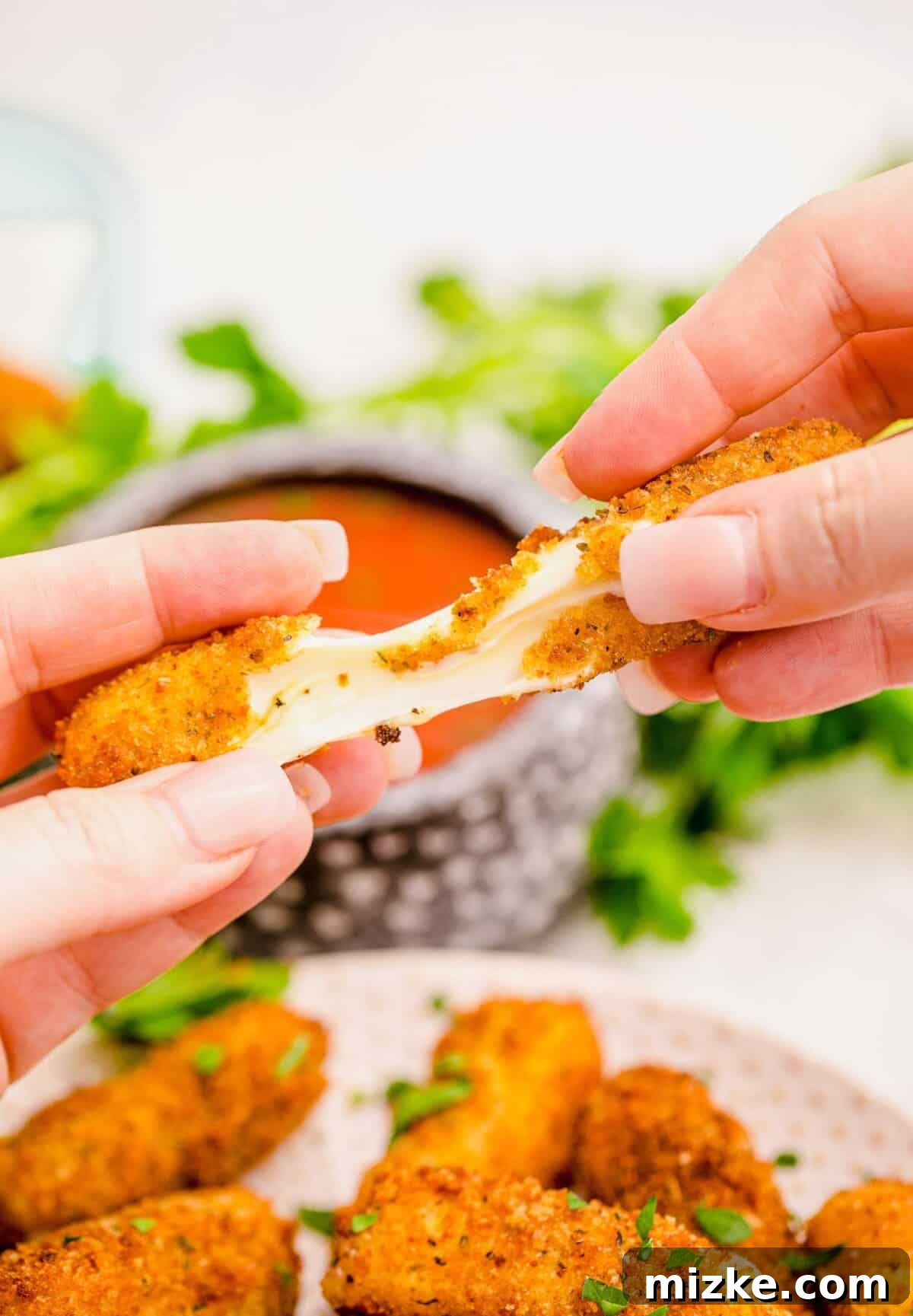 Irresistible Homemade Mozzarella Sticks 11 pulling apart a fried mozzarella stick