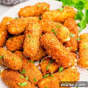 mozzarella sticks on a white plate next to fresh parsley