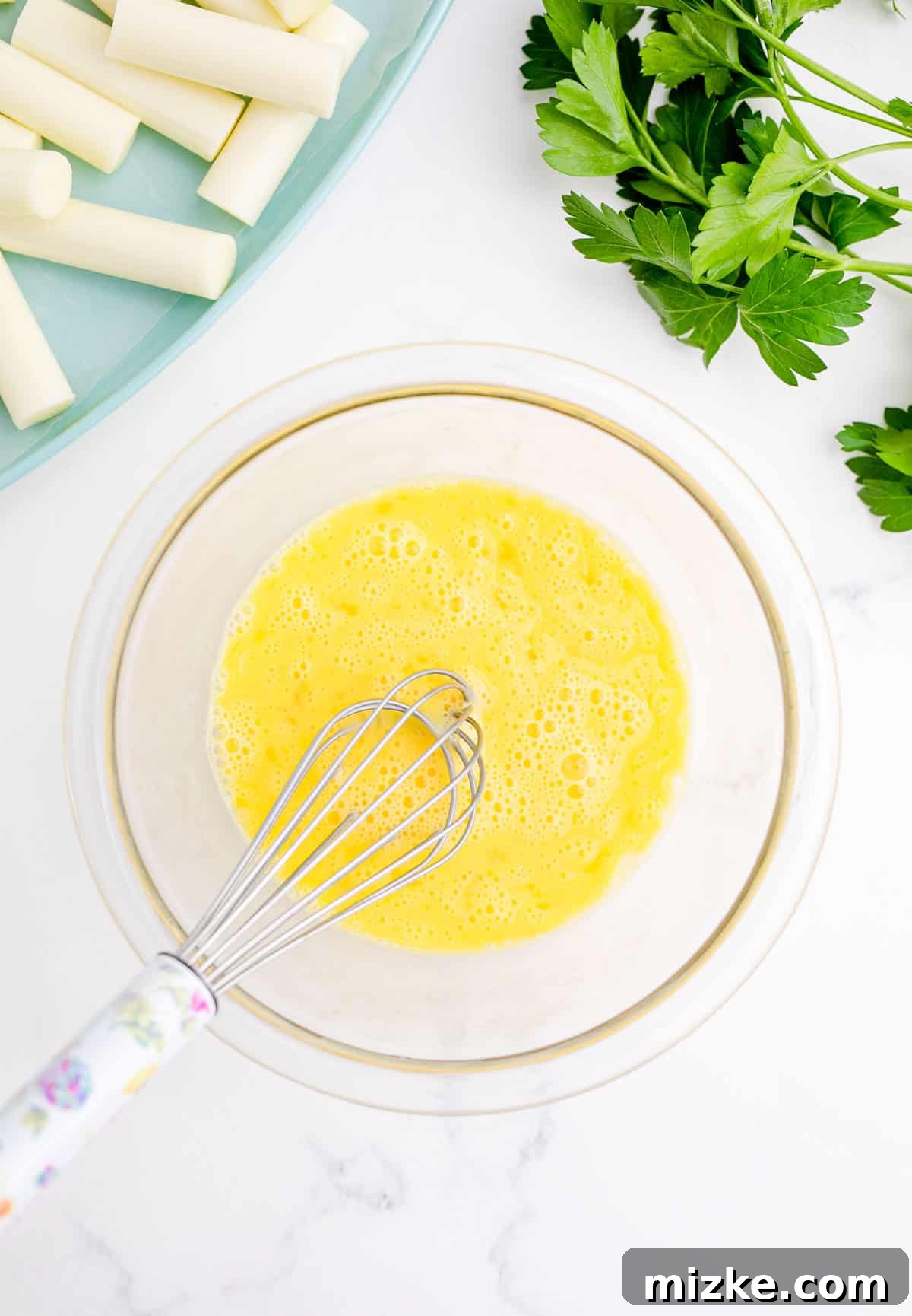 Irresistible Homemade Mozzarella Sticks 5 whisking eggs in a clear bowl