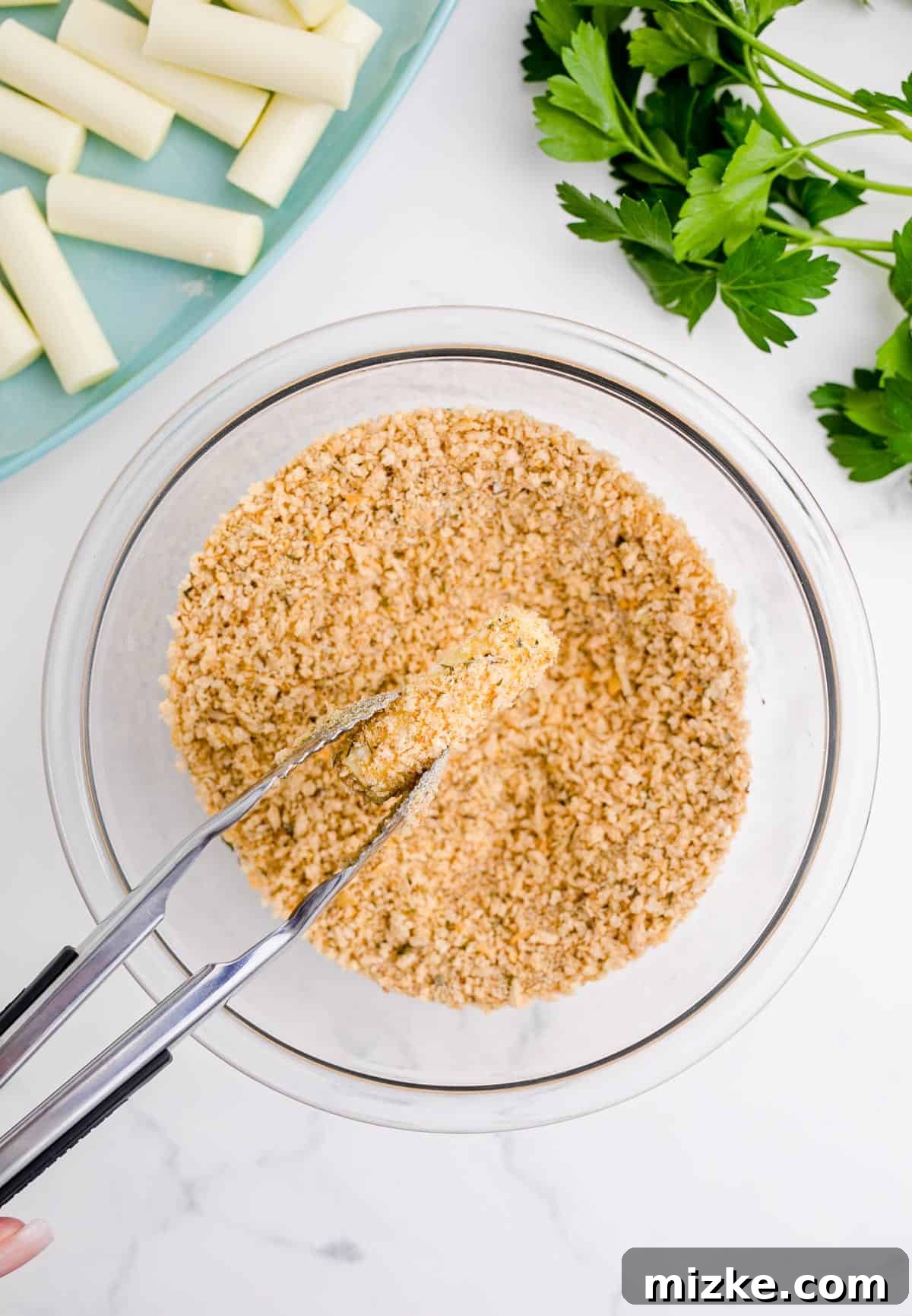 Irresistible Homemade Mozzarella Sticks 7 dipping the mozzarella stick into the breadcrumb mixture with a metal tong
