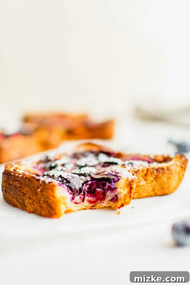 Creamy Yogurt Custard Toast 4 A single slice of custard toast with a bite taken out, revealing its soft, creamy interior and golden crust.