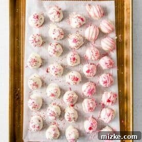 decorated and dipped red velvet cake balls on a parchment paper lined baking sheet