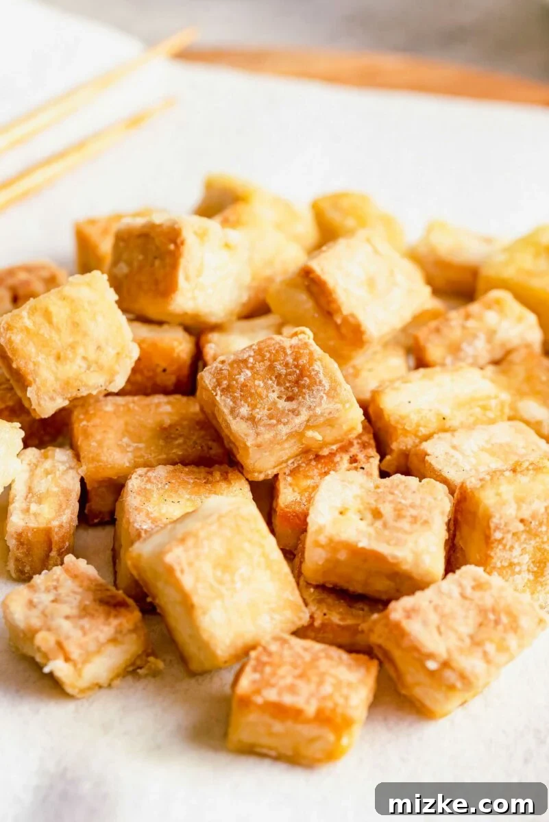 Beyond Bland: Unlock Tofu's Flavor Secrets 23 Crispy pieces of tofu on a plate, tossed with a flavorful sauce