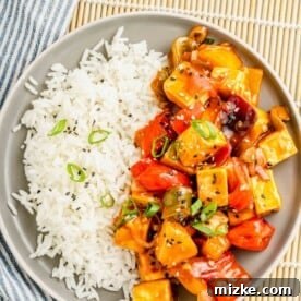 tofu, veggies, and rice are presented together on a single round plate.