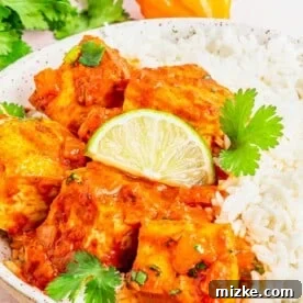 Coconut Caribbean Tofu in bowl with white rice, garnished with lime wedge and cilantro