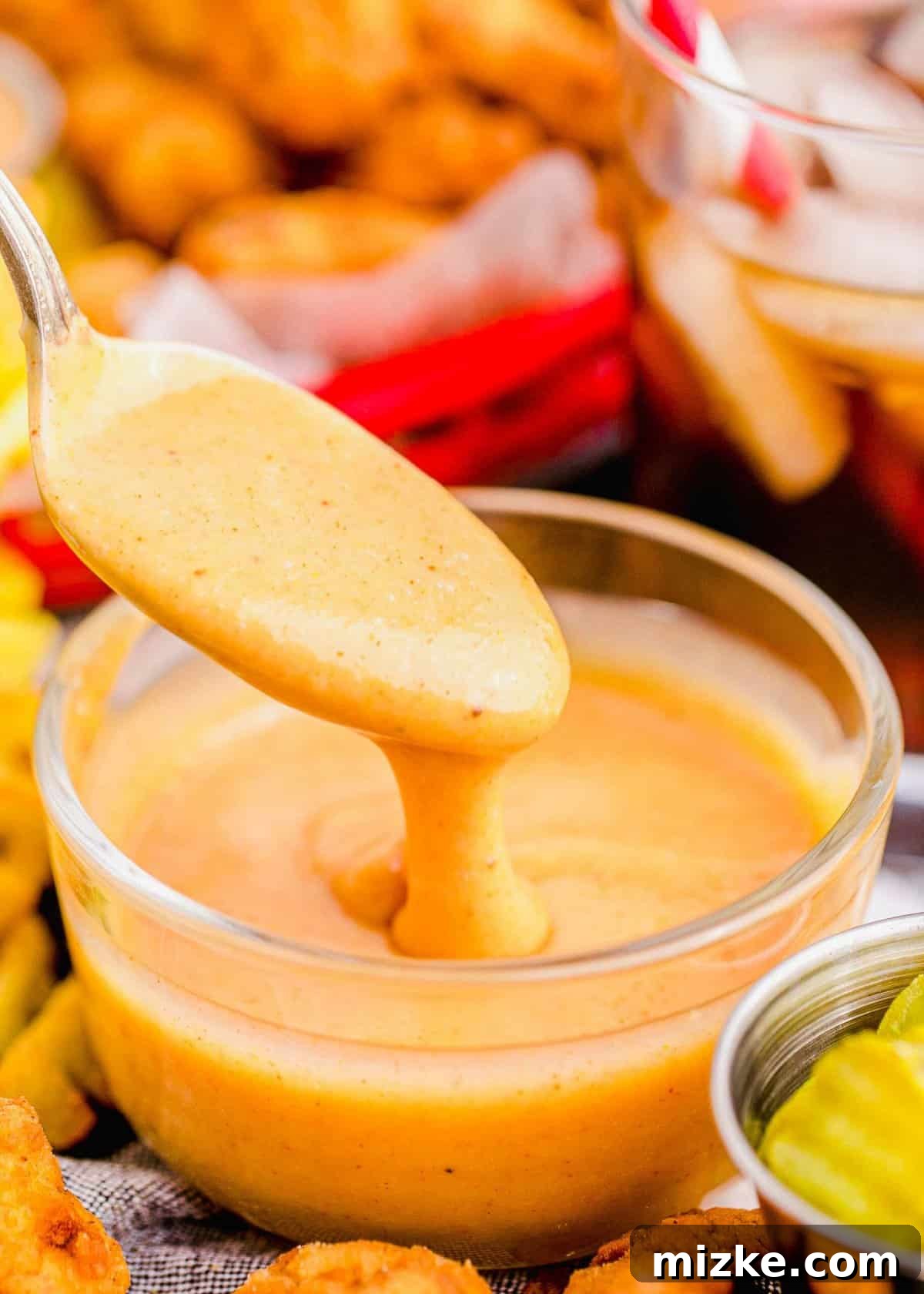 Restaurant Style Chick-Fil-A Sauce 3 Spoonful of Chick-Fil-A sauce dripping into small glass bowl of sauce