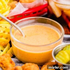 Glass bowl of Chick-Fil-A sauce, surrounded by nuggets and fries