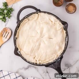 Velvety Chicken Alfredo Pot Pie 11 Puff pastry covering the alfredo pot pie mixture in a cast iron skillet, with slits cut into the top.