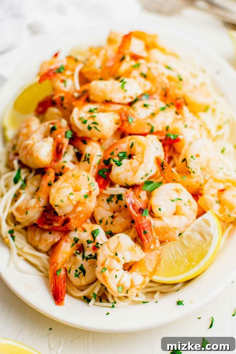 Sizzling Lemon Garlic Shrimp 3 A plate of shrimp scampi is topped with fresh herbs and a lemon wedge.