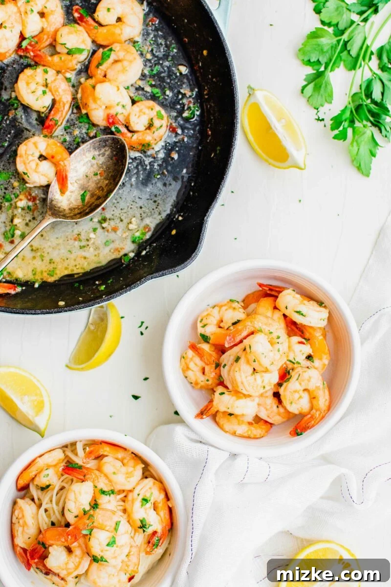 Sizzling Lemon Garlic Shrimp 4 Two white bowls of cooked shrimp are placed next to a black skillet.