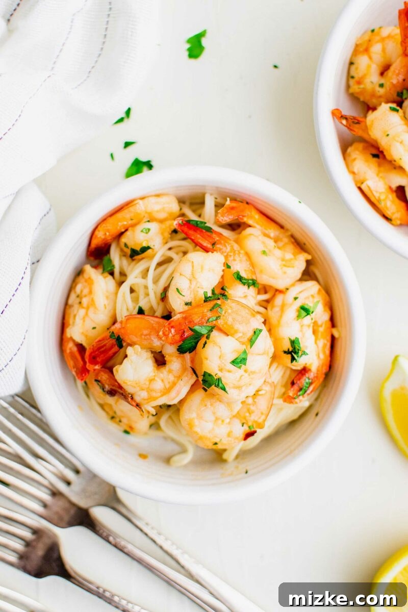 Sizzling Lemon Garlic Shrimp 5 A white bowl is filled with pasta, shrimp, and topped with fresh parlsey.