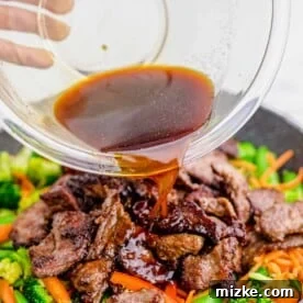 Rich stir fry sauce being poured over the beef and vegetables in the skillet, ready to thicken and coat.