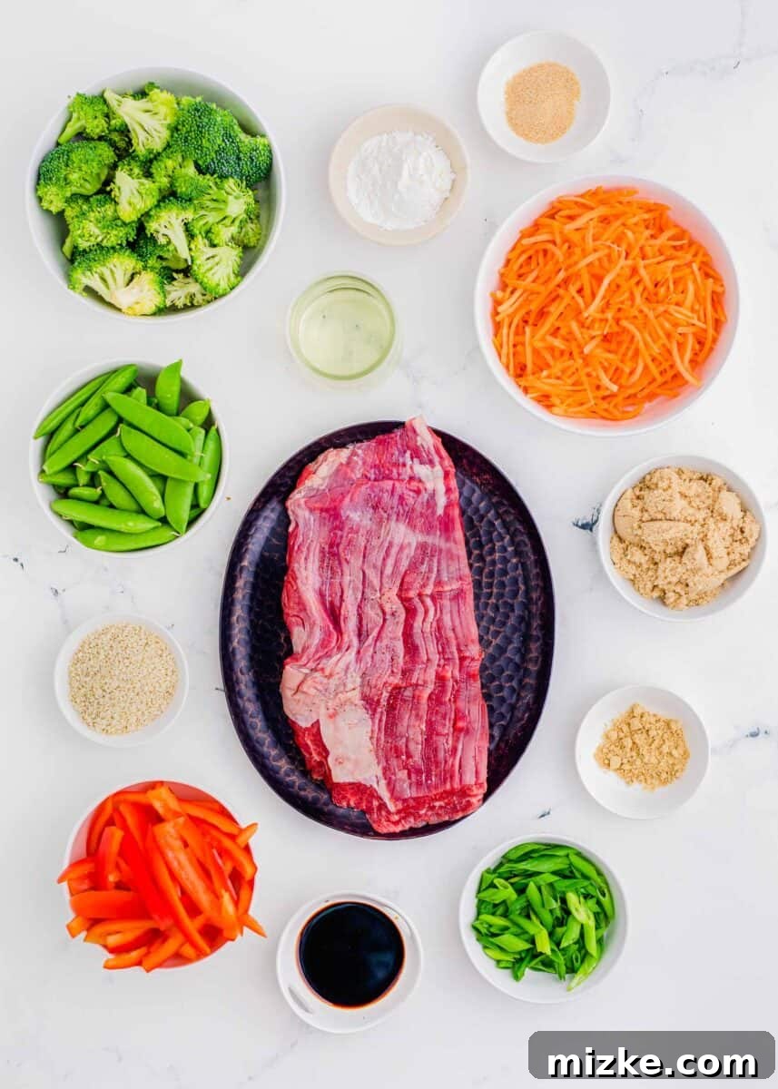 Sizzling Beef Stir Fry 3 Overhead image displaying fresh ingredients for beef stir fry, including broccoli florets, cornstarch, minced garlic, shredded carrots, brown sugar, ground ginger, sliced green onions, soy sauce, red bell peppers, sesame seeds, and snow peas.