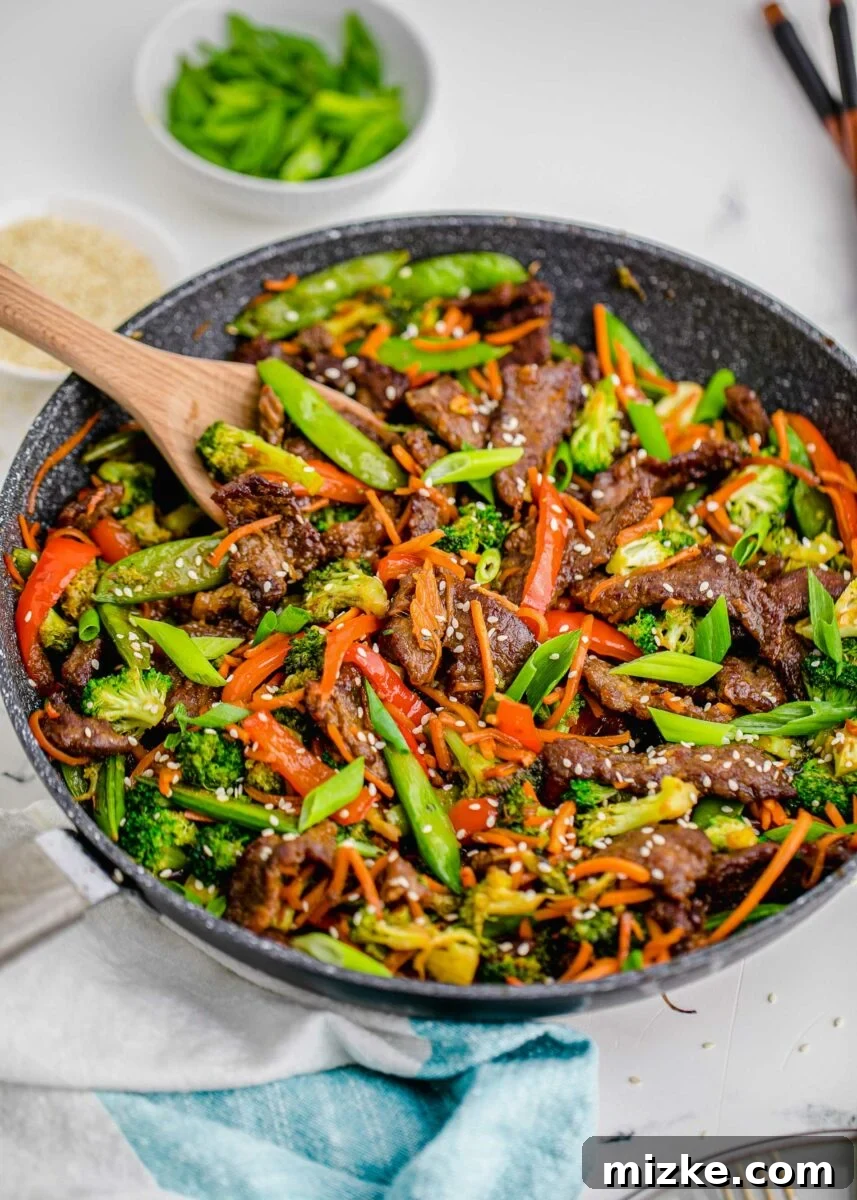 Sizzling Beef Stir Fry 4 A large skillet is filled with beautifully cooked steak, vibrant vegetables, and a glossy stir fry sauce, garnished with sesame seeds.