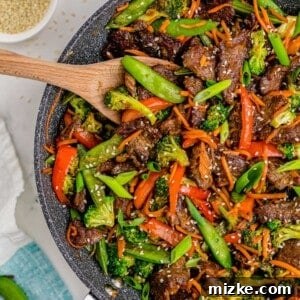 A close-up image of a delicious serving of beef stir fry with white rice, garnished with green onions.