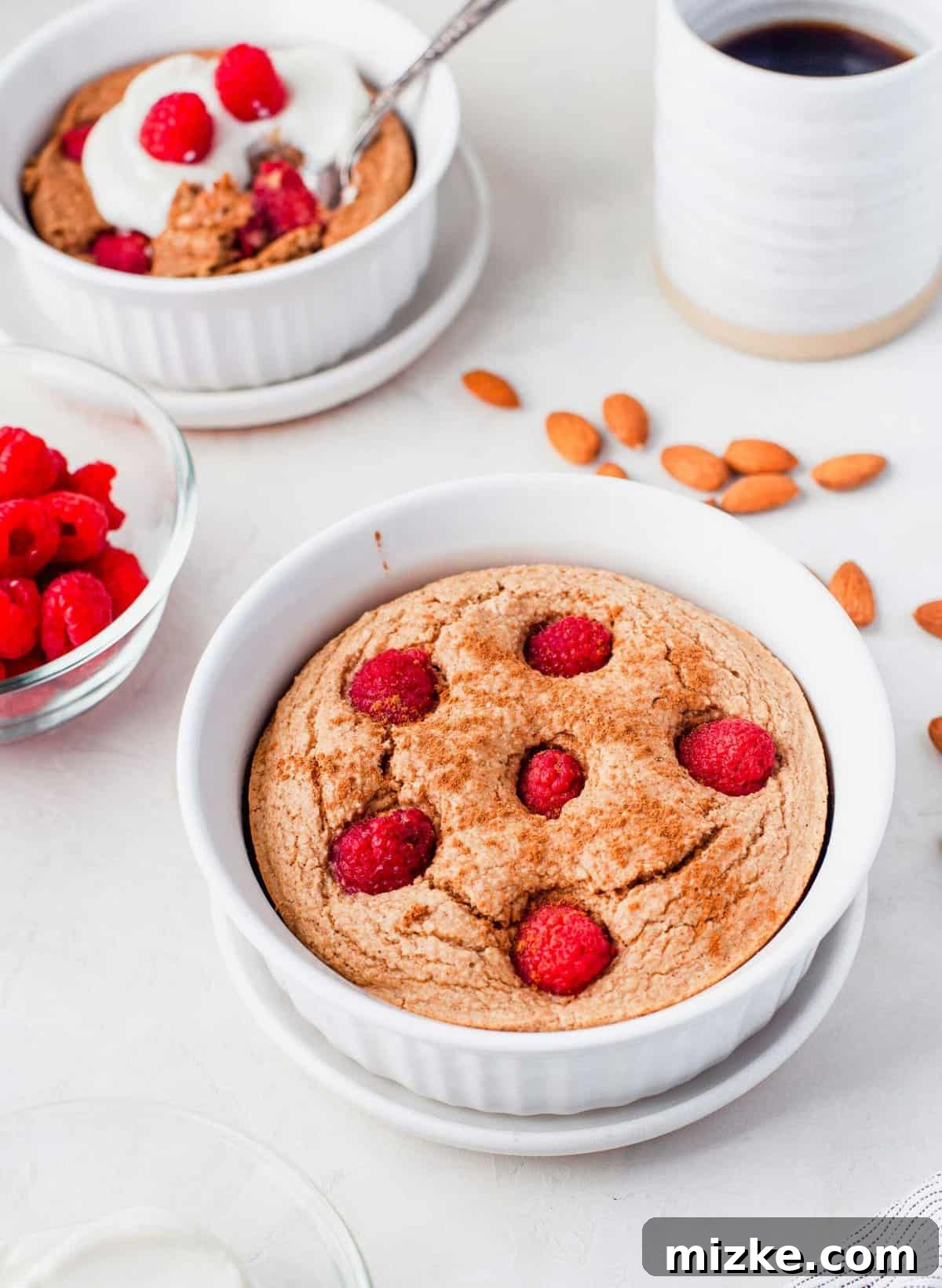Raspberry Oatmeal Bake 5 An individual serving of baked raspberry oatmeal in a white bowl, freshly baked and ready for topping, highlighting its inviting and fluffy appearance.