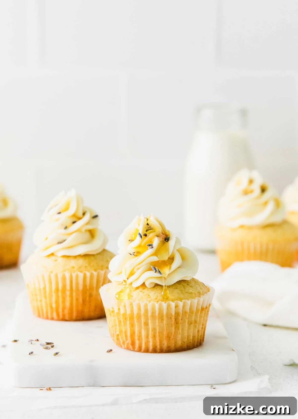 Blossom Honey Lavender Cupcakes 7 A close-up of a Honey Lavender Cupcake, featuring a generous swirl of honey buttercream and an artful drizzle of honey, inviting a taste.