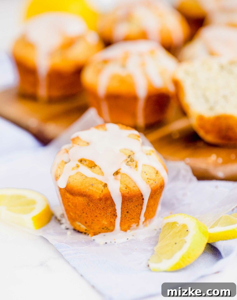 Zesty Lemon Poppy Seed Muffins 6 A glazed lemon poppyseed muffin is placed on a tea towel next to fresh lemon slices, highlighting its fresh appeal.