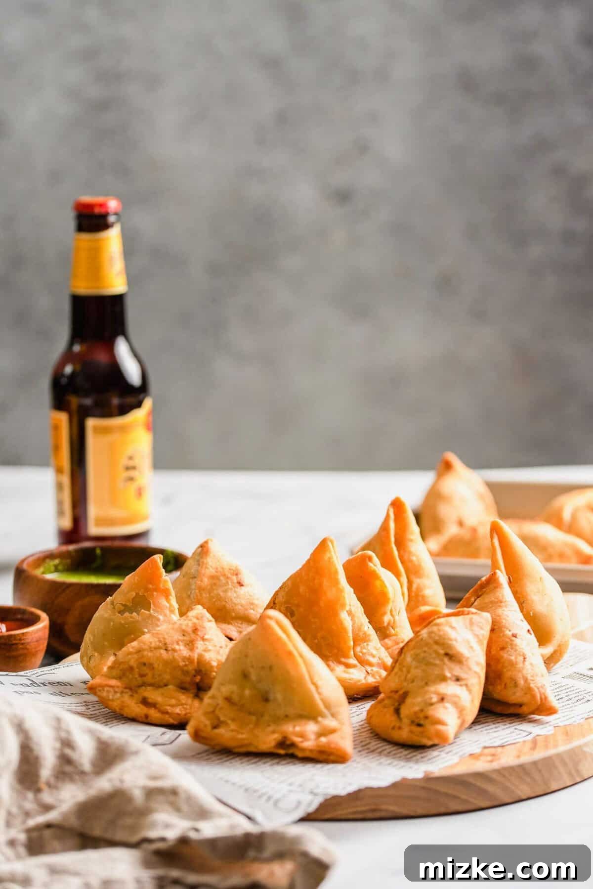 Golden Crispy Vegetable Samosas 3 Crispy vegetable samosas neatly arranged on a cutting board lined with paper towels, showcasing their golden-brown perfection.