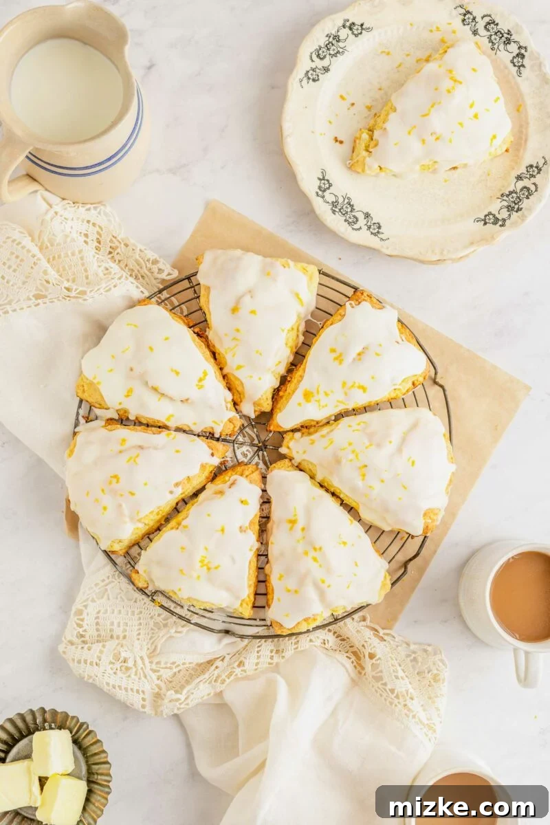Seven golden-brown orange scones are arranged in a circle on a wire cooling rack, placed over a square sheet of parchment paper, ready for glazing.