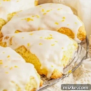 A close-up of a perfectly glazed orange scone, garnished with orange zest, suggesting its delicious homemade quality.